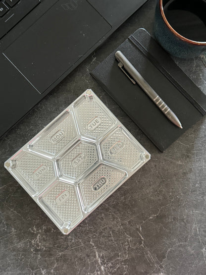 Open raw machined Vitamin Vault Mini on a desk beside a laptop, notebook and pen.