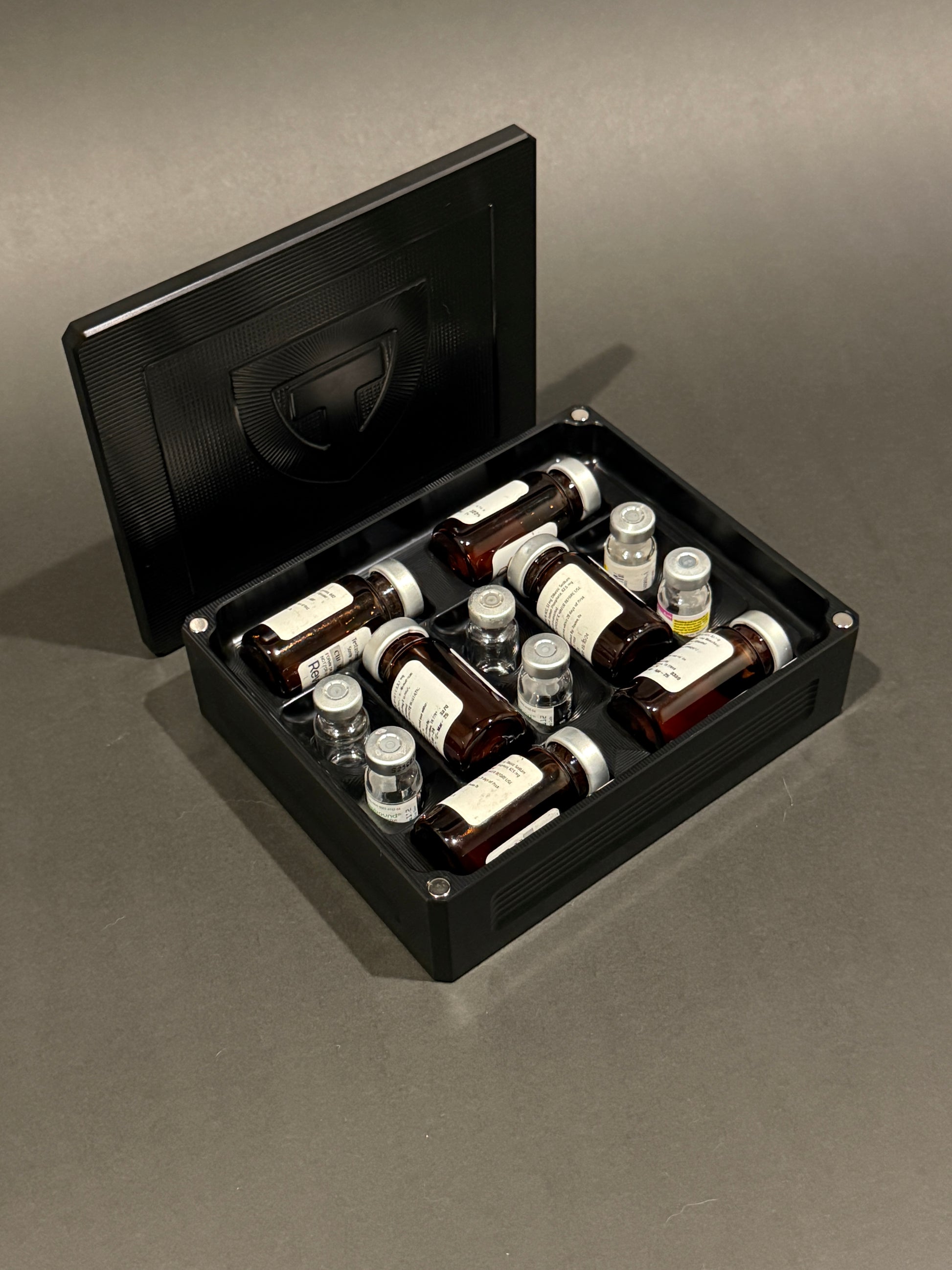Black anodized Peptide Vault Mini shown open and loaded with large and small peptide vials.