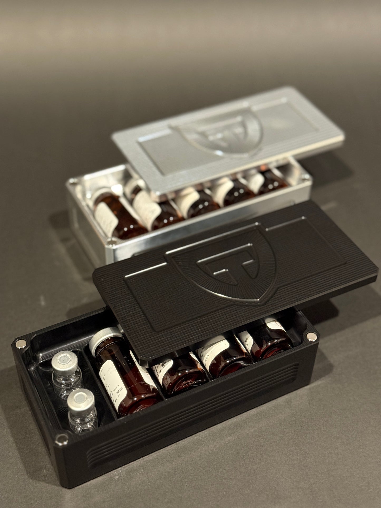 Raw aluminum and black anodized Peptide Vault Micro organizers shown open with peptide vials.