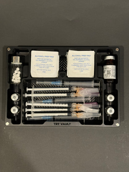 Overhead view of TRT Vault Mega in Anodized Black holding vials, syringes, alcohol swabs and pill vial
