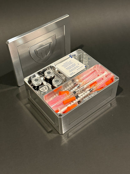 Raw Machined Cycle Vault Mini holding upright vials, a pill vial, syringes and alcohol swabs, with its magnetic lid behind it.