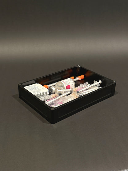 Flex Vault Mega Lidless in anodized black, filled with syringes, vials, and injection supplies on a gray surface.