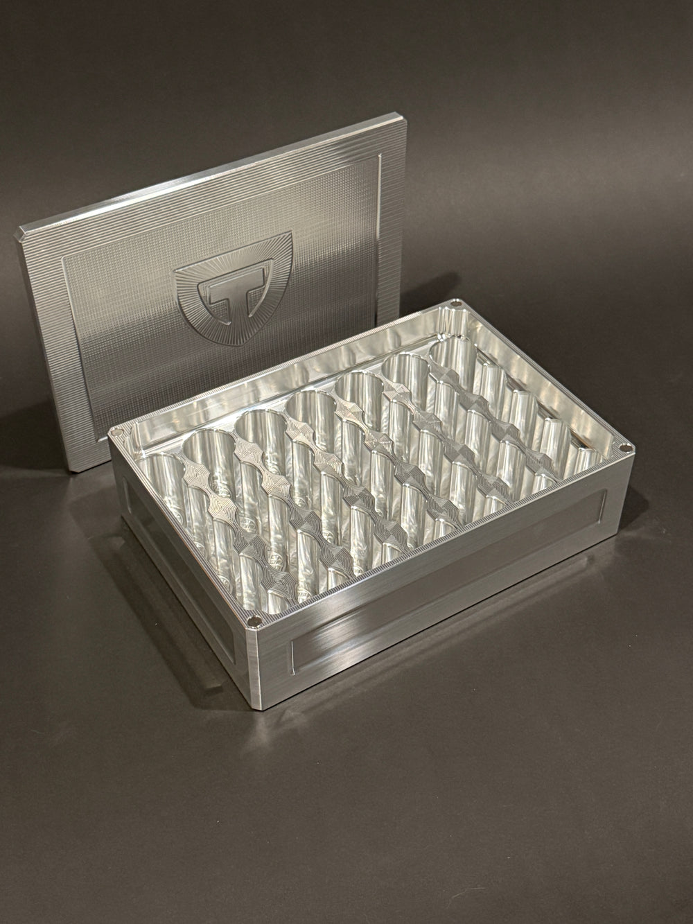 Raw machined Vial Vault Mega shown open and empty with magnetic lid and precision-machined vial storage slots.