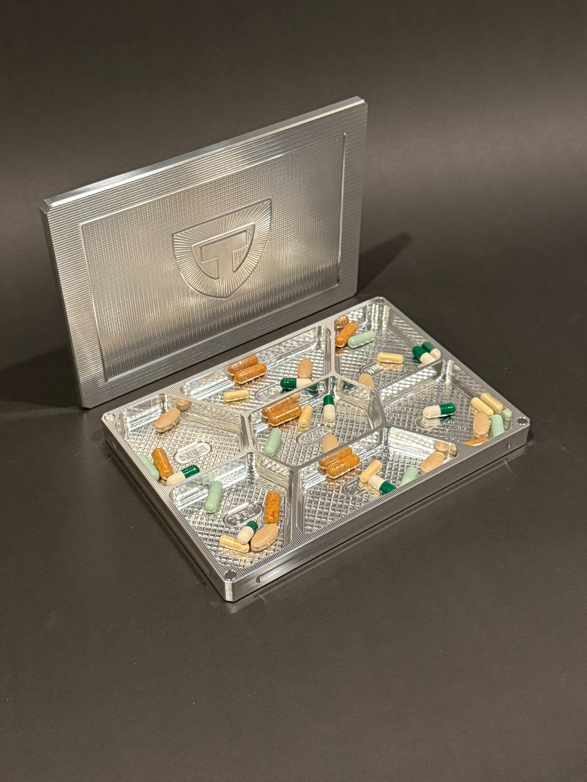 Raw Machined Vitamin Vault Mega shown open with its magnetic lid, filled with tablets and capsules.