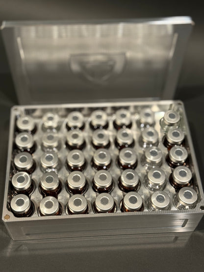 Raw machined Vial Vault Mega shown open and filled with assorted vials from an overhead angle, with the magnetic lid behind it.