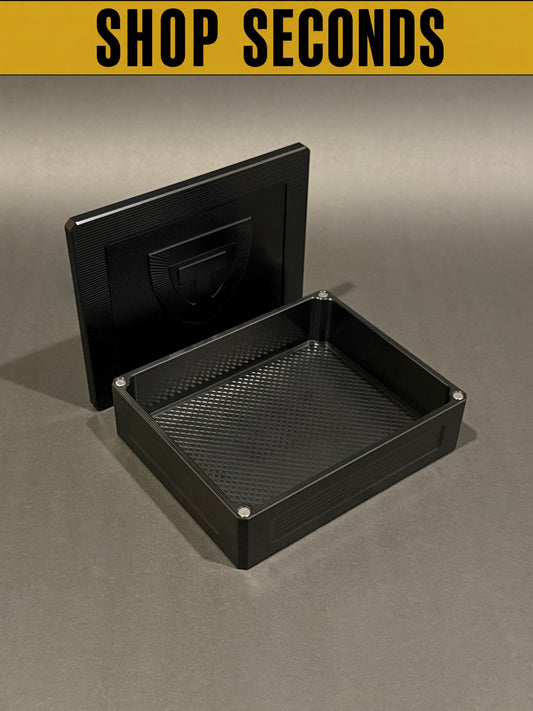 Shop Seconds anodized black Flex Vault Mini shown open and empty with magnetic lid and large storage compartment.
