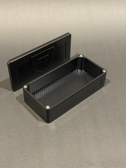 Anodized black Flex Vault Micro shown empty with its removable lid standing behind it.