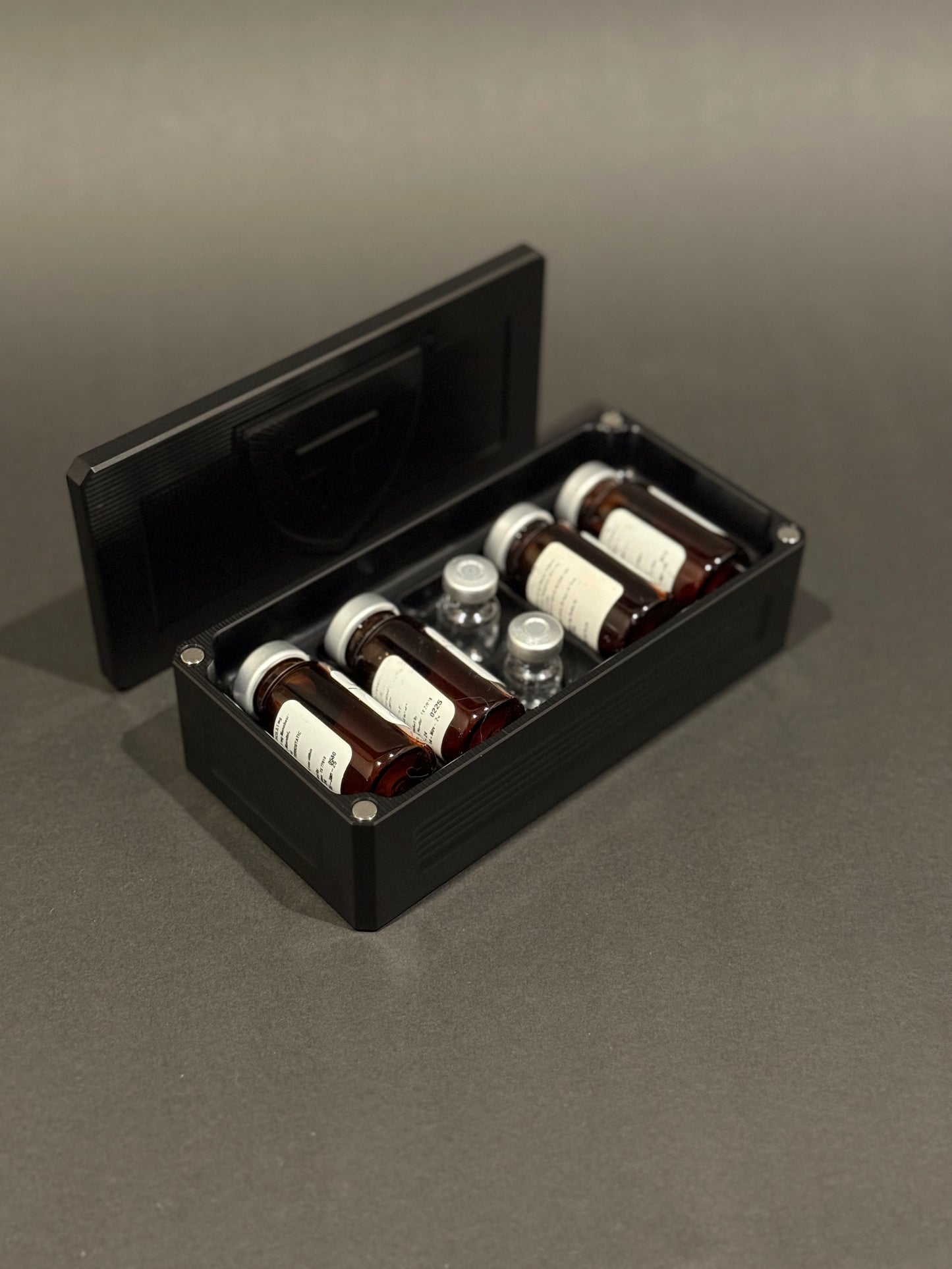 Black anodized Peptide Vault Micro shown open and loaded with peptide vials.