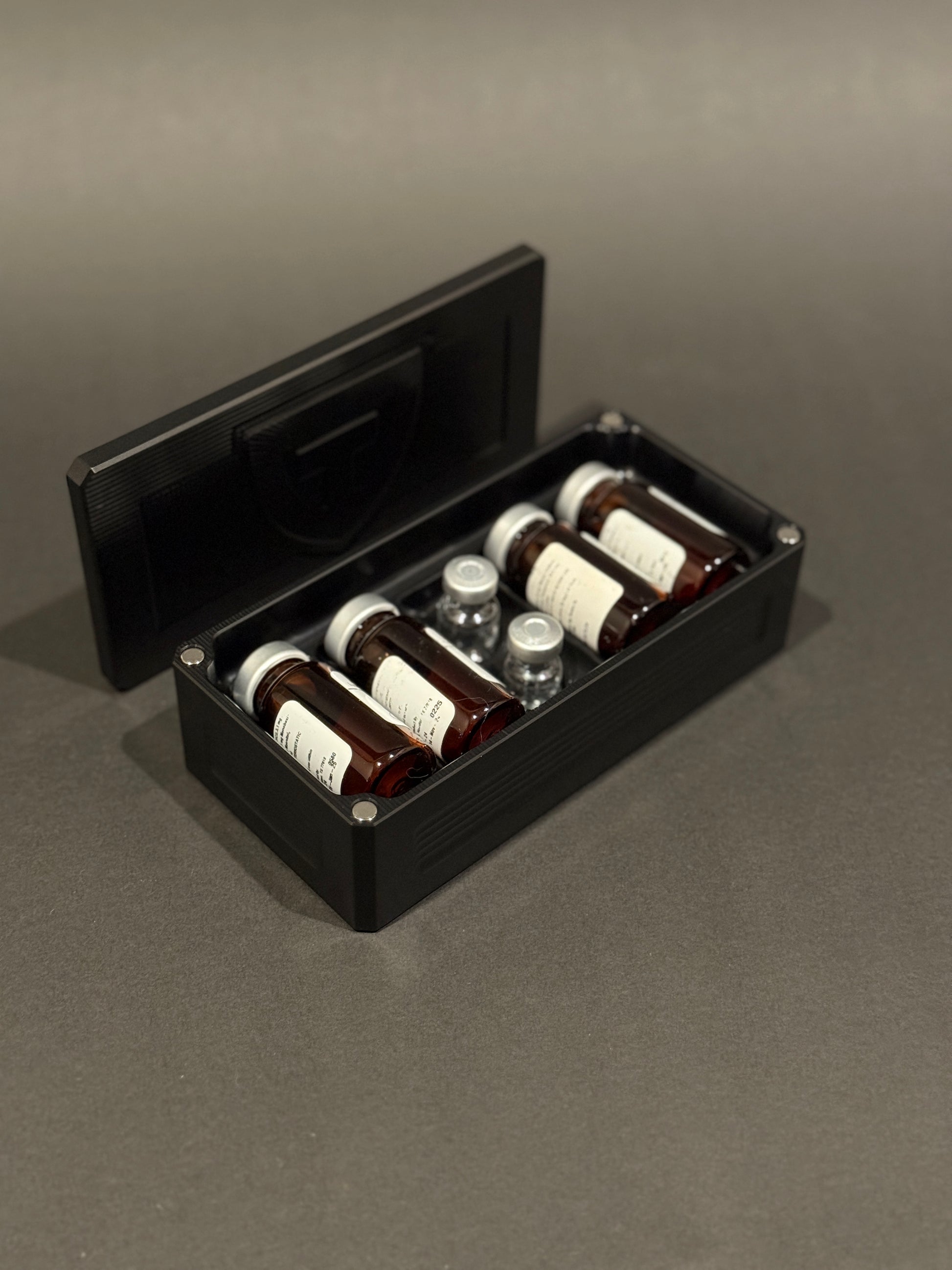 Black anodized Peptide Vault Micro shown open and loaded with peptide vials.