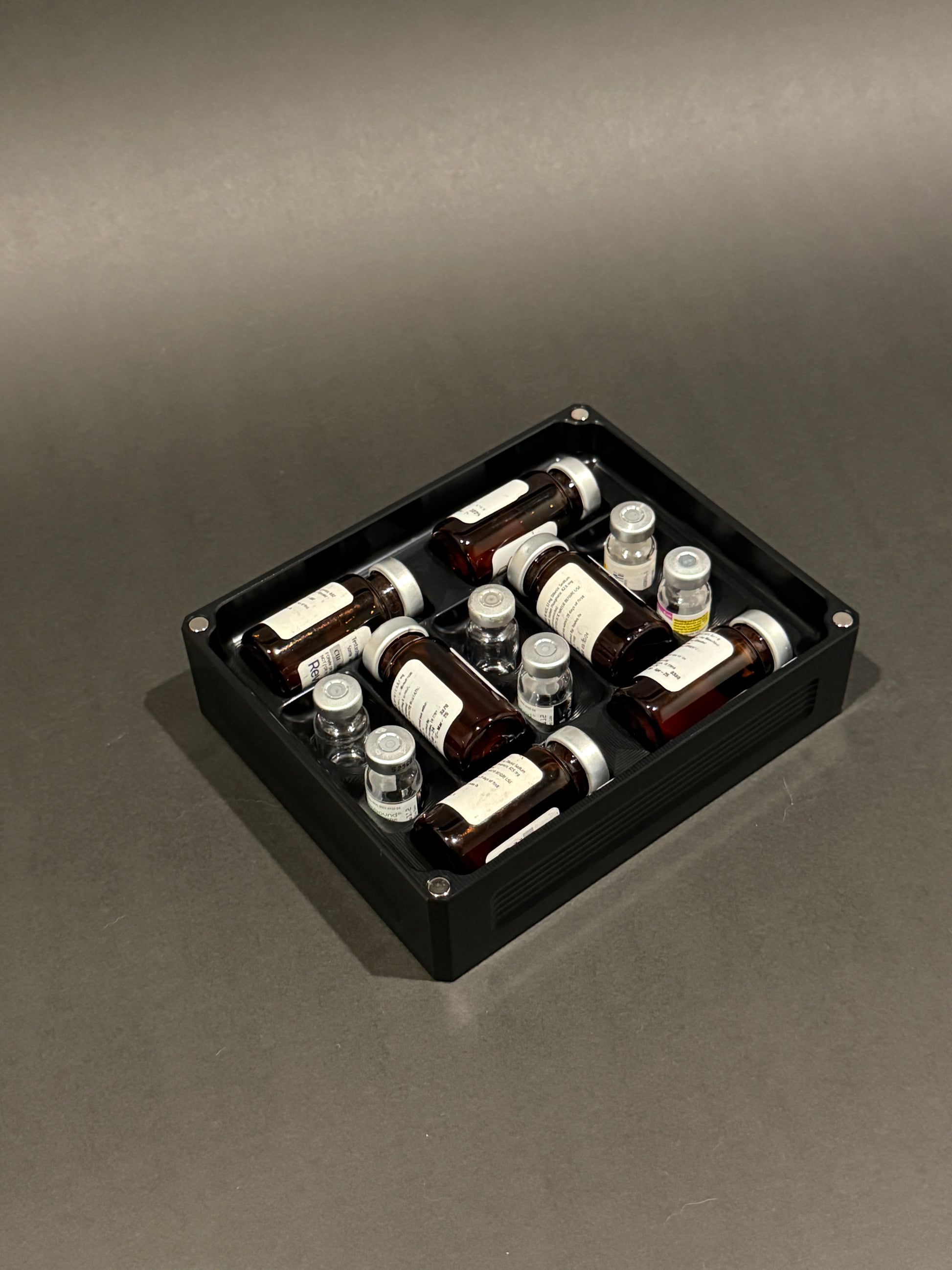 Peptide Vault Mini Lidless in Anodized Black holding small vials