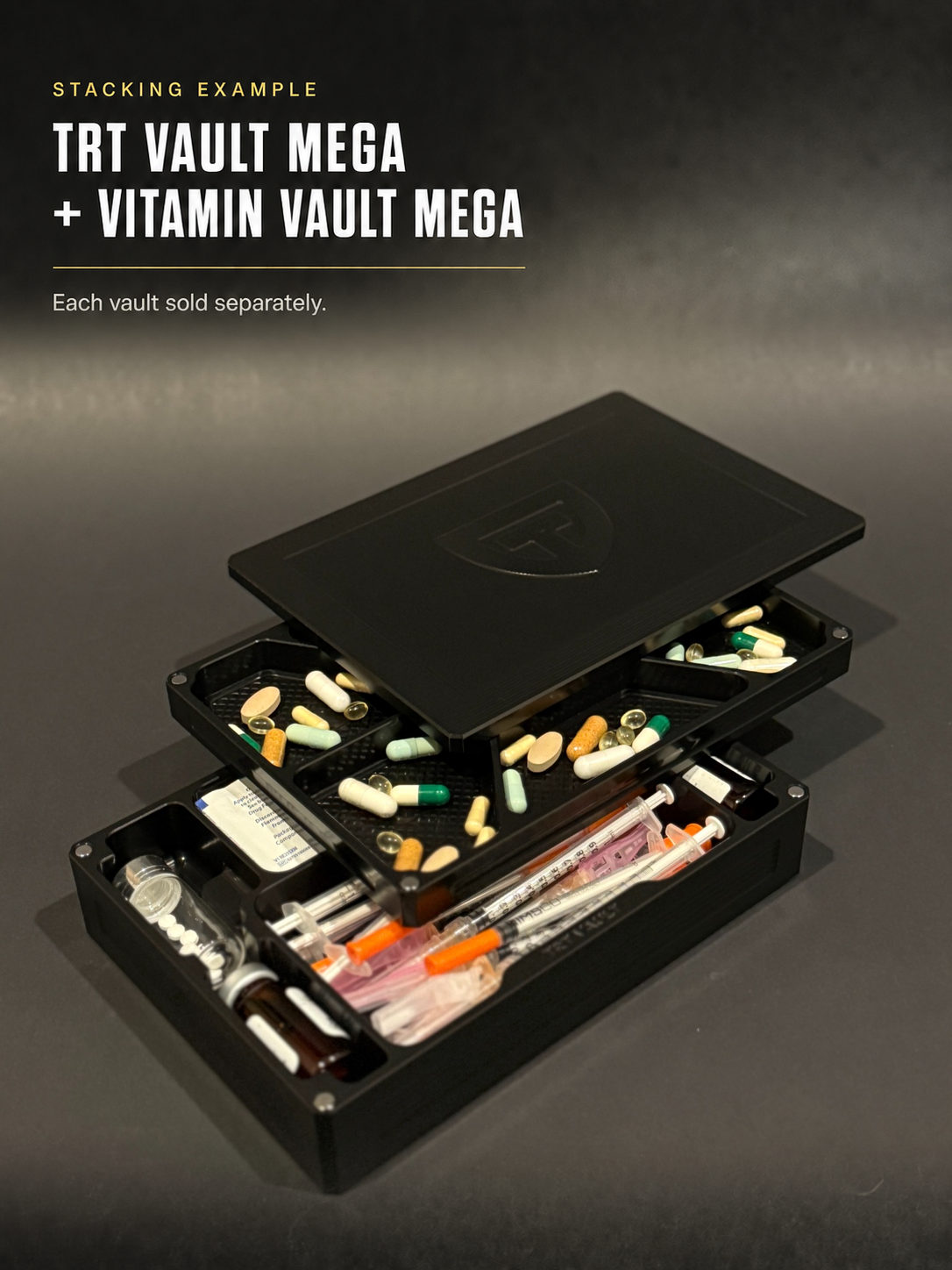 Open Black Anodized TRT Vault Mega with vials and syringes stacked beneath a Vitamin Vault Mega with pills; each vault sold separately