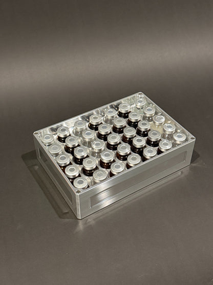 Lidless Vial Vault Mega in Raw Machined, filled with clear and amber glass vials standing upright.
