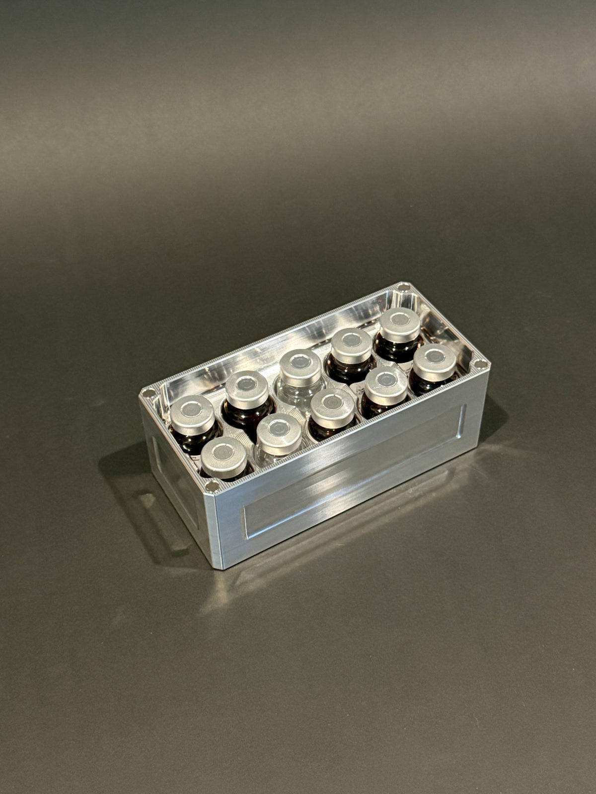 Lidless Vial Vault Micro in Raw Machined, filled with clear and amber glass vials standing upright.
