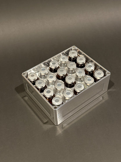 Lidless Vial Vault Mini in Raw Machined, filled with clear and amber glass vials standing upright.